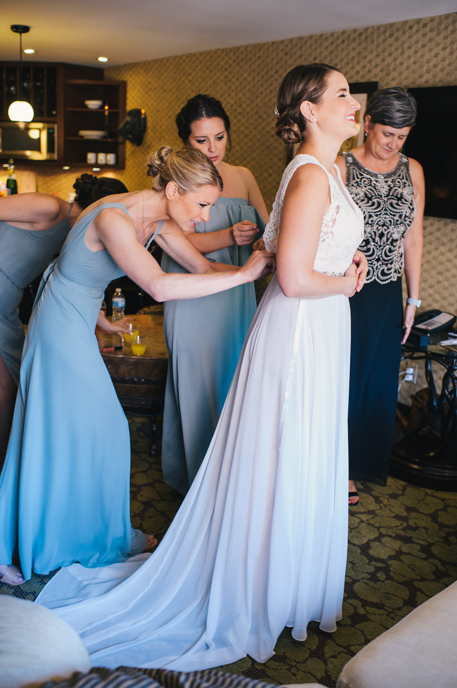 bridesmaids buttoning the back of the bride's dress